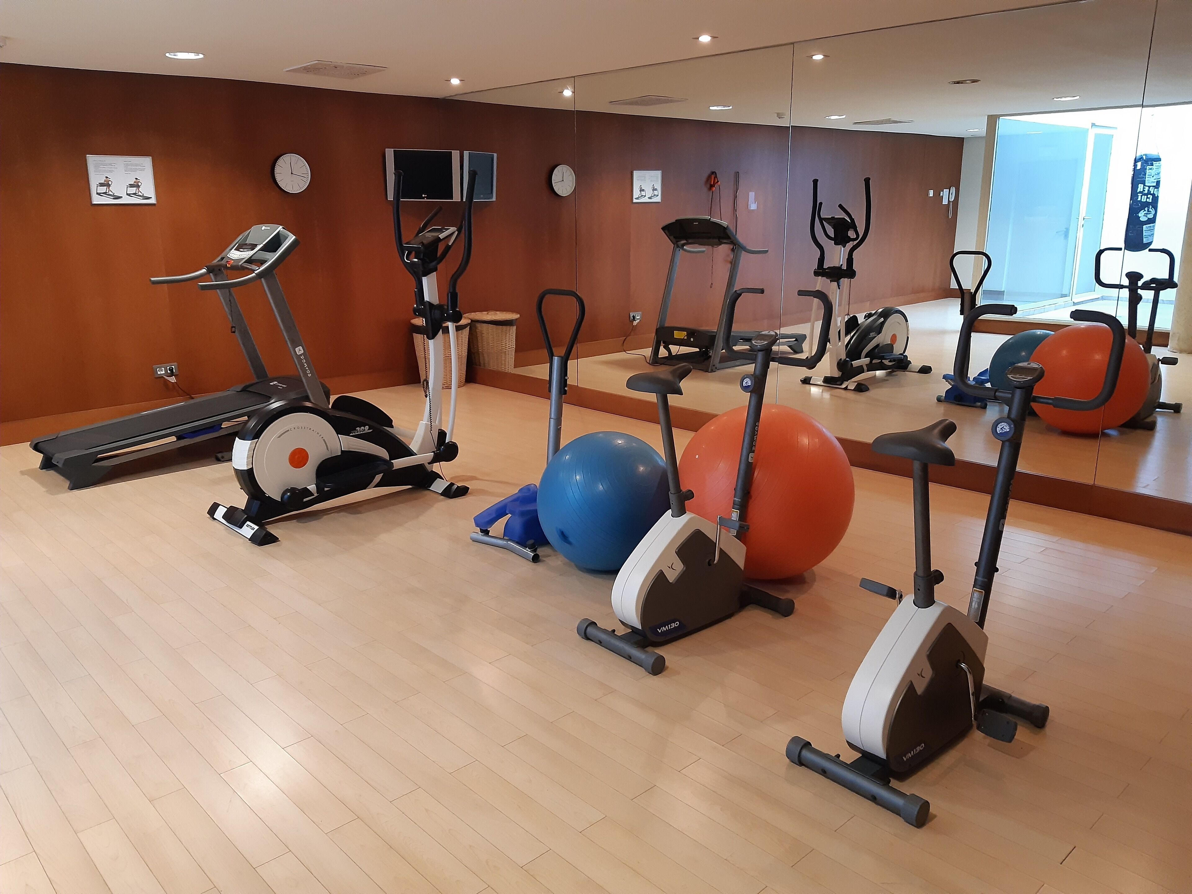 Una palestra con diverse attrezzature per l'allenamento, tra cui tapis roulant, ellittiche e palle da ginnastica.
