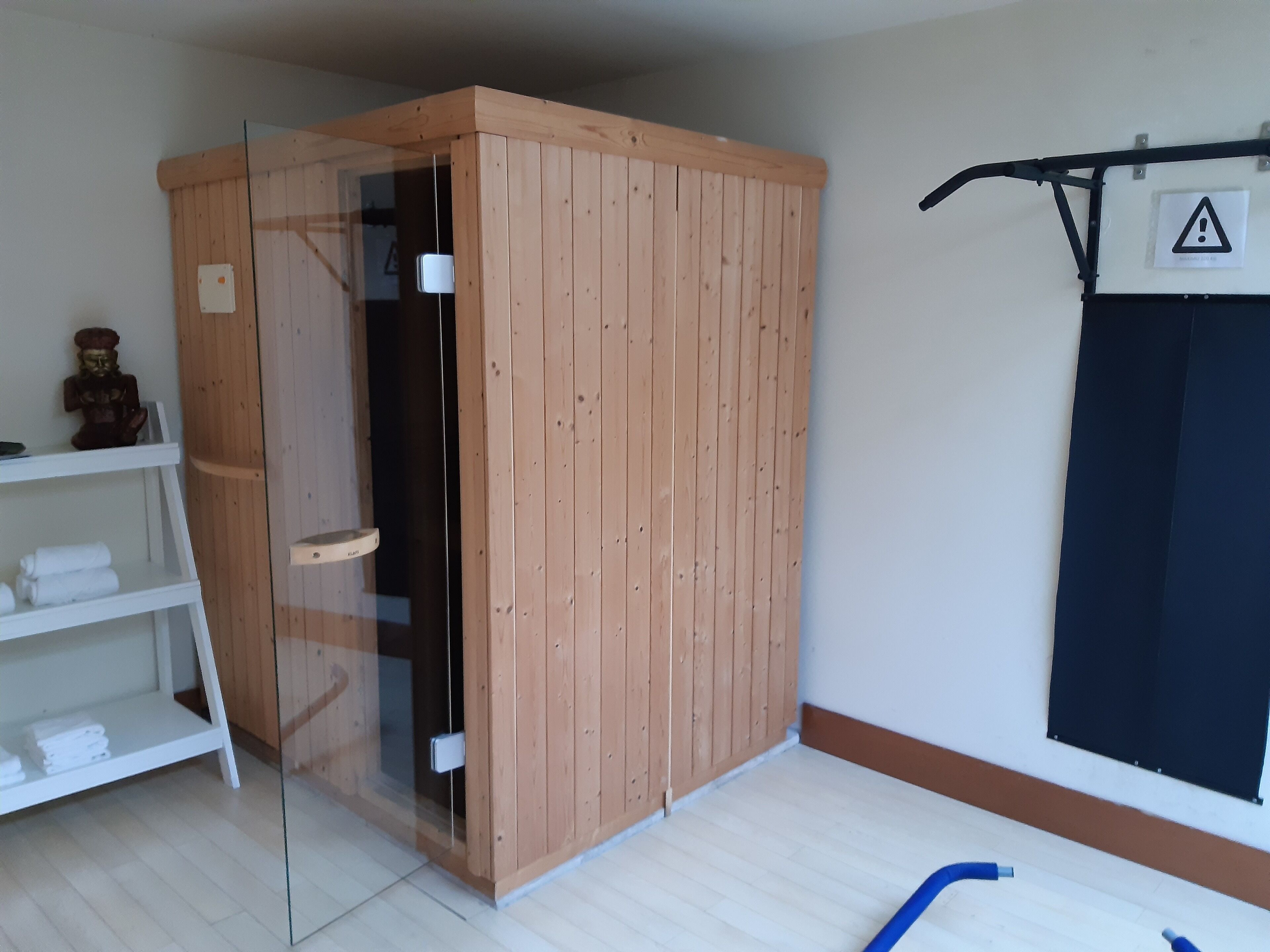 Una habitación con un armario de madera, un vidrio, un estante blanco con toallas y una cortina negra.