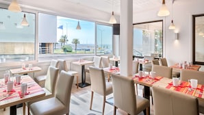 A modern dining area with tables and chairs, large windows, and pendant lighting. - Best Western Hotel Royan Ocean (Royan)