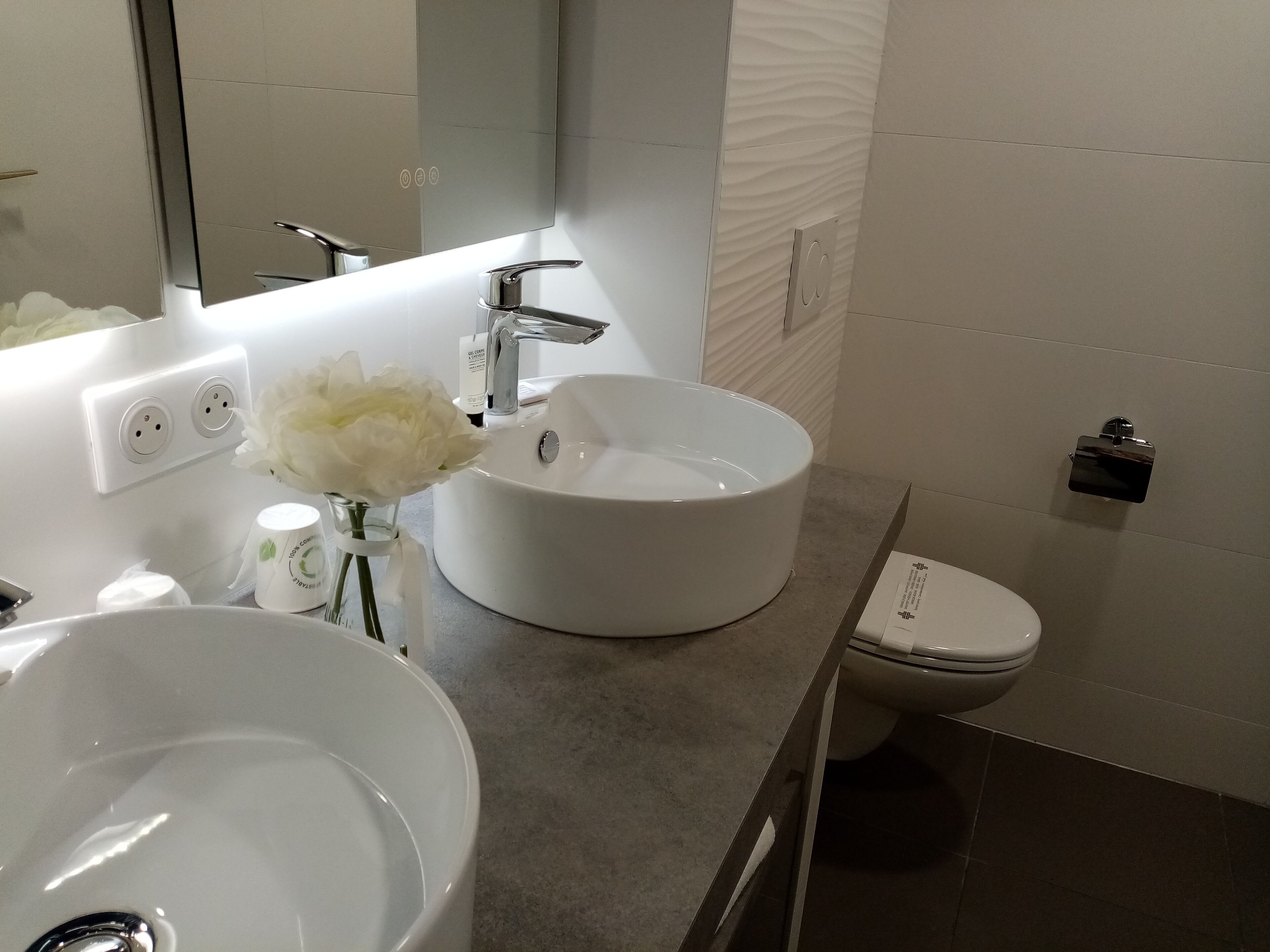 Un baño moderno con un lavabo blanco, un espejo y un inodoro.