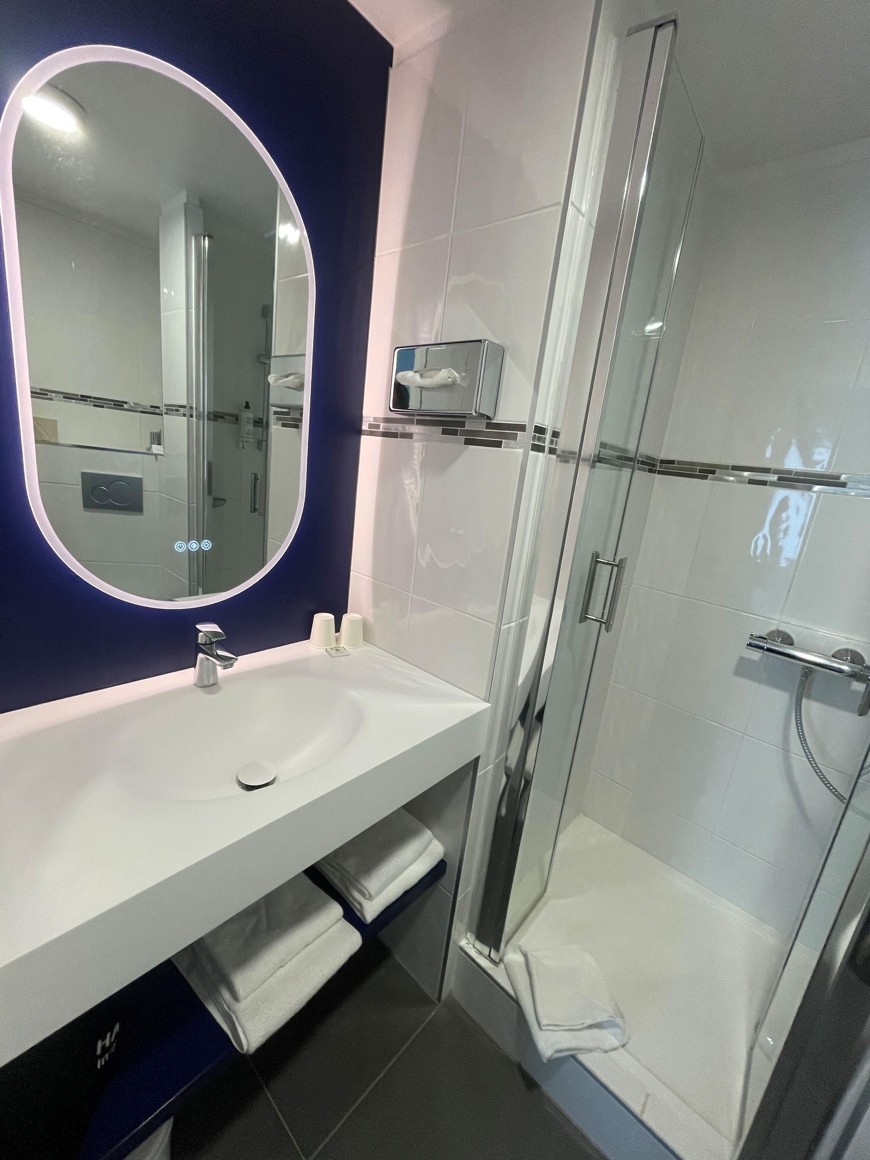 A modern bathroom with a white sink, a large mirror, and a glass shower enclosure.
