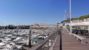 A marina with numerous boats docked, a Ferris wheel in the background, and a boardwalk with outdoor seating. - Best Western Hotel Royan Ocean (Royan)