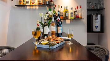 A dining table with seafood, wine glasses, and a variety of liquor bottles on shelves behind.