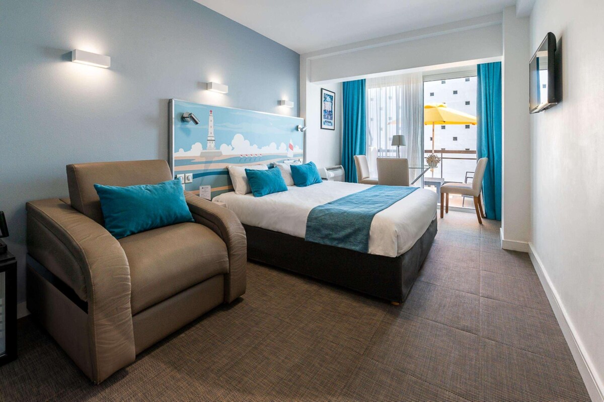 A hotel room with a bed, a sofa, a desk, and a chair.