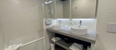 A modern bathroom with two sinks, a shower, and a bathtub.