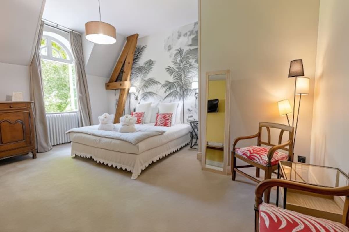 A bedroom with a bed, a wooden dresser, a chair, and a lamp.