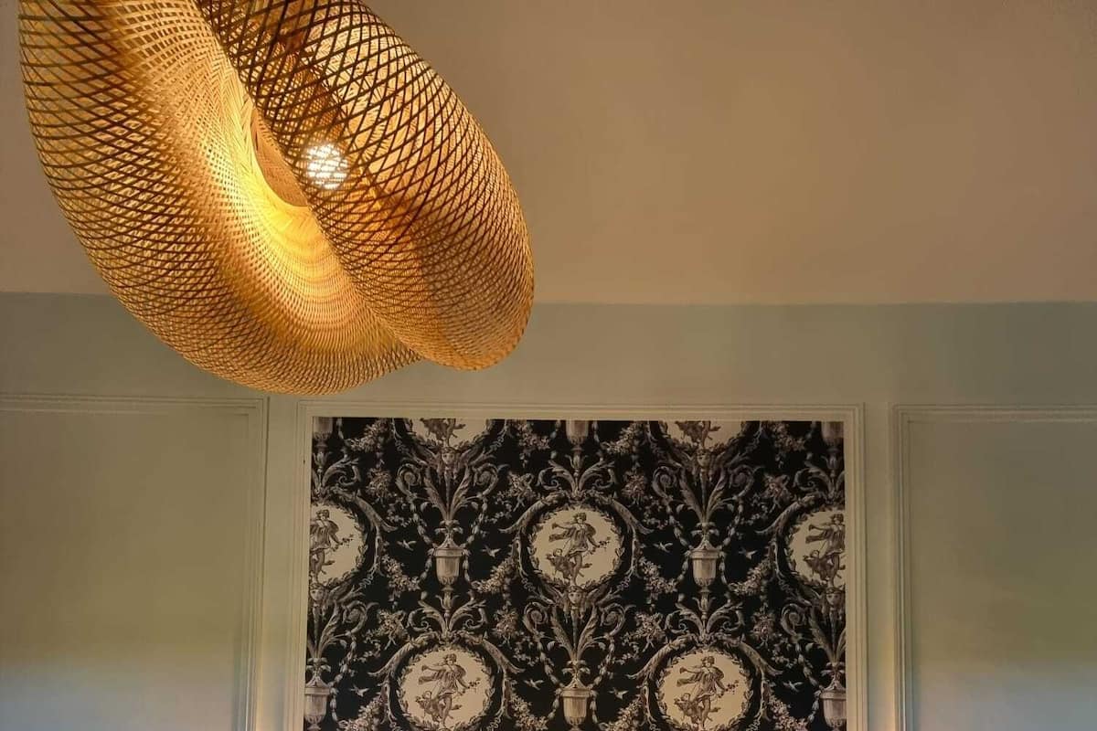 Una habitación de hotel con una cama grande, dos mesitas de noche, un tapiz decorativo y una lámpara colgante.