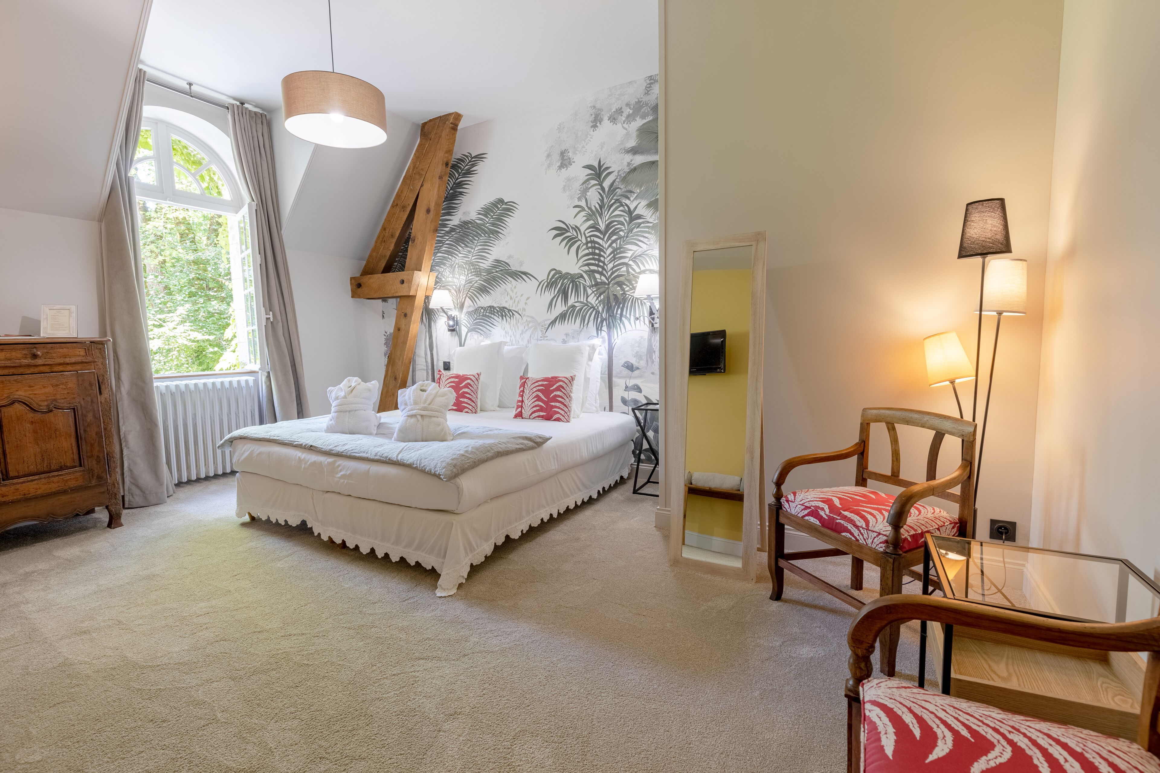 A bedroom with a bed, a wooden dresser, a chair, and a lamp.