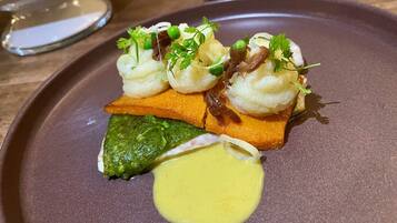 A plate with a dish consisting of a green vegetable, a yellow sauce, and a piece of orange food.