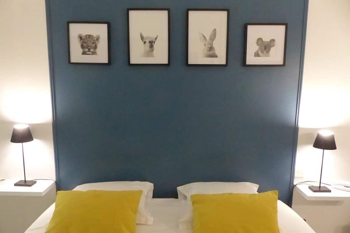 A hotel room with a bed, two nightstands, and four framed animal portraits on the wall.