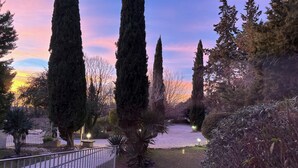 A garden pathway with tall cypress trees and a metal fence. - La Sommellerie (Chateauneuf-du-Pape)