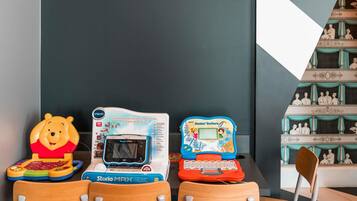 Trois tablettes éducatives sont posées sur une table, devant laquelle se trouvent des chaises.