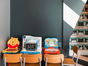 Trois tablettes éducatives sont posées sur une table, devant laquelle se trouvent des chaises.