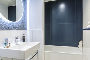 Ein modernes Badezimmer mit einem weißen Waschbecken, einem Chromarmaturen und einem großen Spiegel.