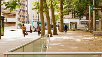 Rua urbana com pedestres, ponto de ônibus e edifícios.