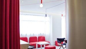 A modern interior with red seating, white tables, and a large cylindrical column. - ibis Styles Paris Mairie de Montreuil (Montreuil)