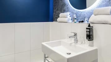 A modern bathroom with a white sink, a mirror with a circular frame, and a blue accent wall.