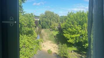 A view from a window overlooking a river, surrounded by lush greenery and trees.