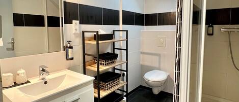 Un baño moderno con tragaluz, un lavamanos blanco, paredes con azulejos blanco y negro, y una zona de ducha.