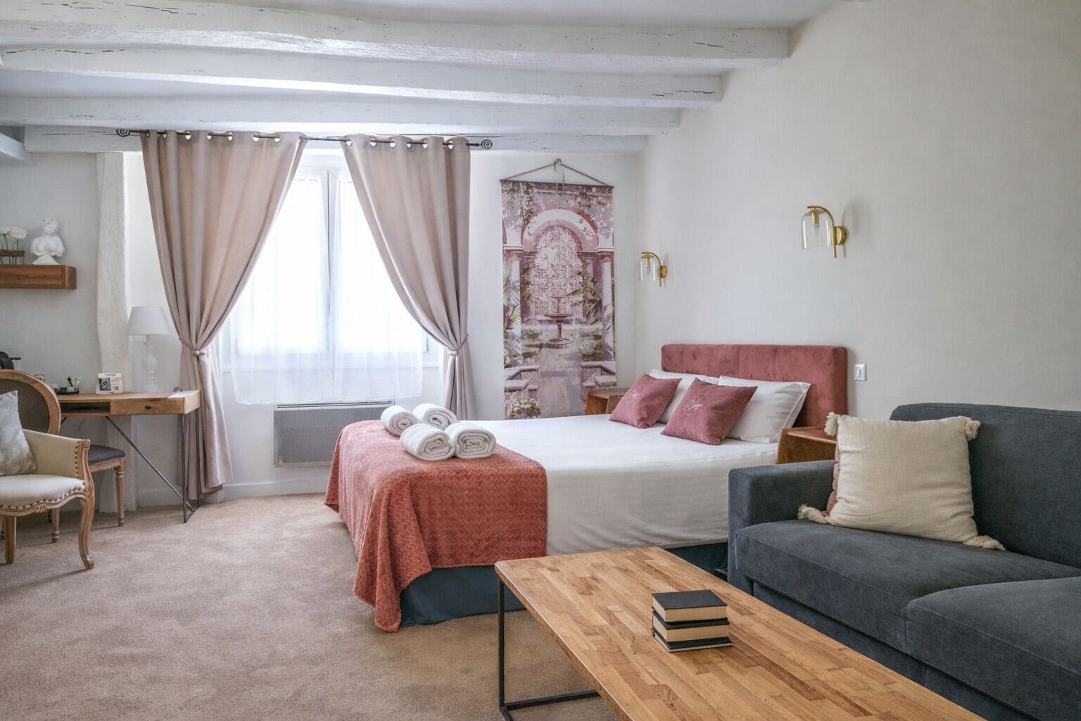 A bedroom with a bed, bedside tables, a desk, a chair, a sofa, and a window with curtains.