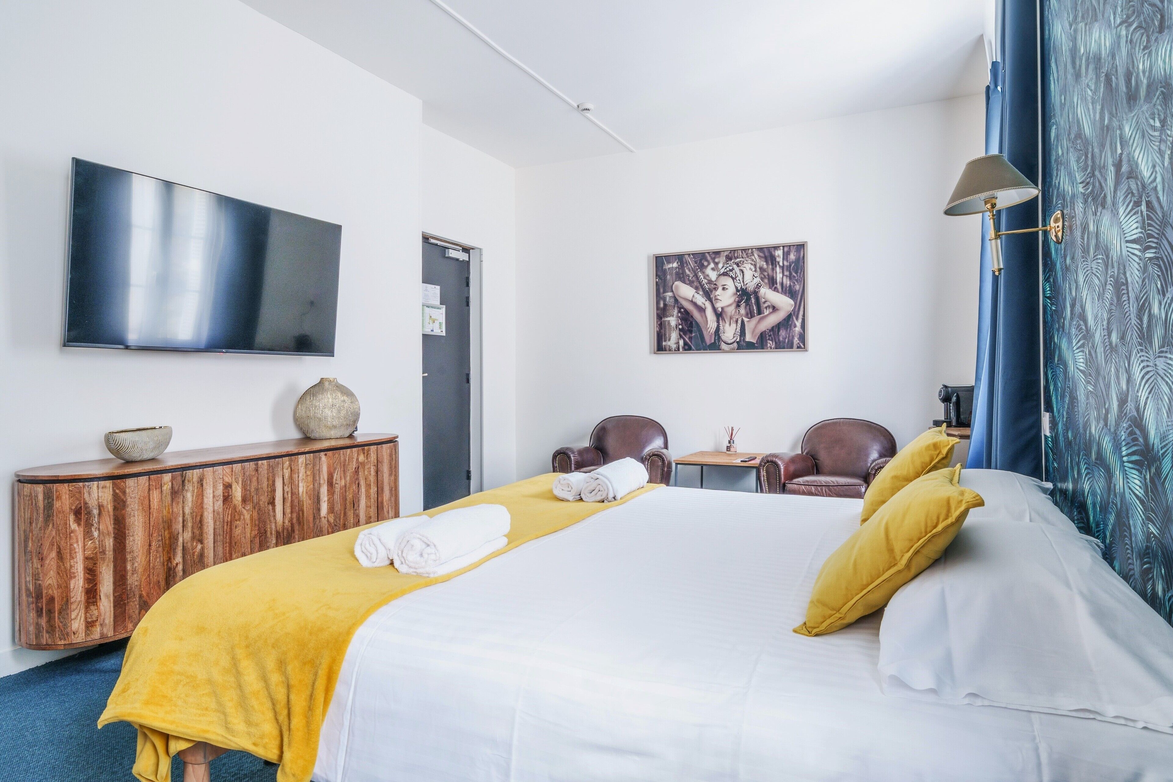 Habitación de hotel con cama, televisor de pantalla plana, un cuadro, escritorio y silla.