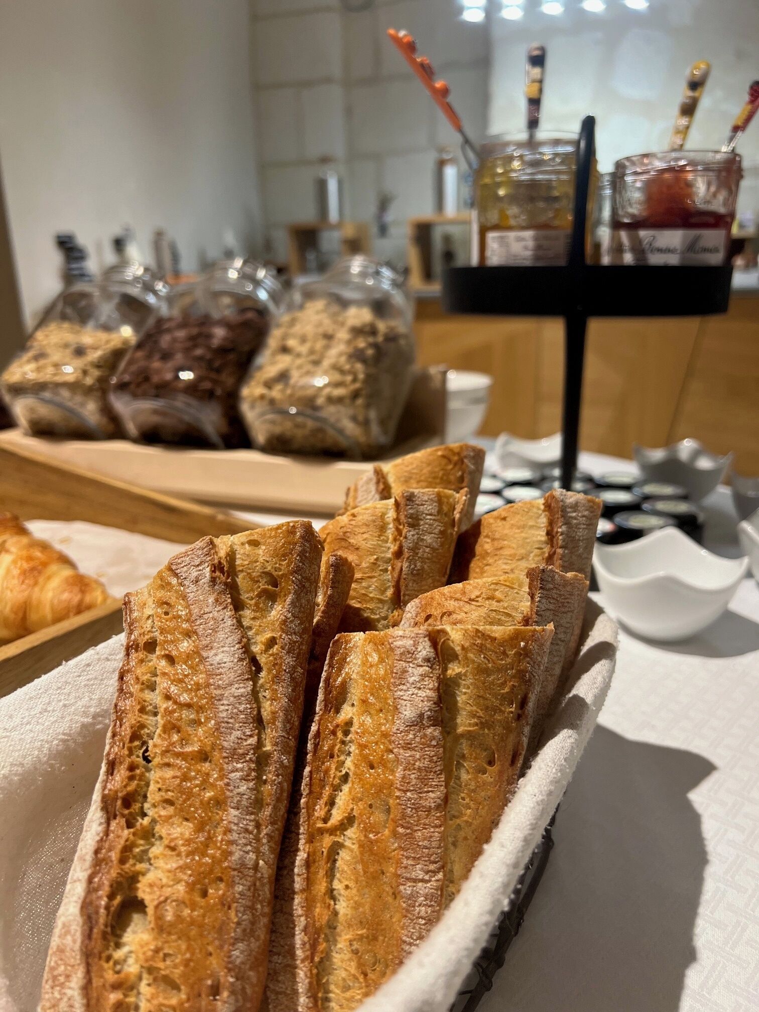 Une assiette de baguettes et des pots de différentes pâtes à tartiner sont posés sur une table.