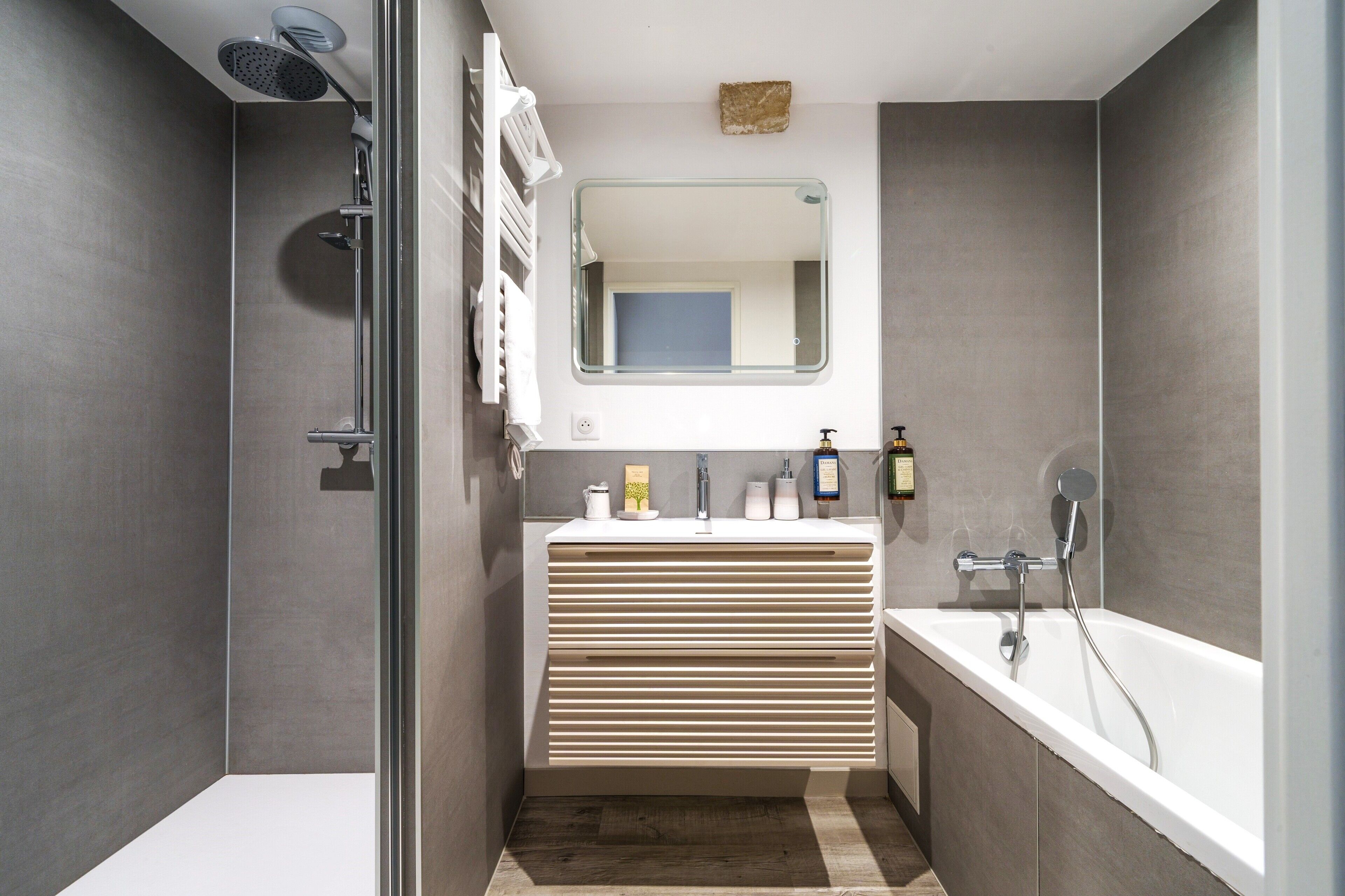 Un bagno moderno con doccia, lavabo con specchio e vasca da bagno.