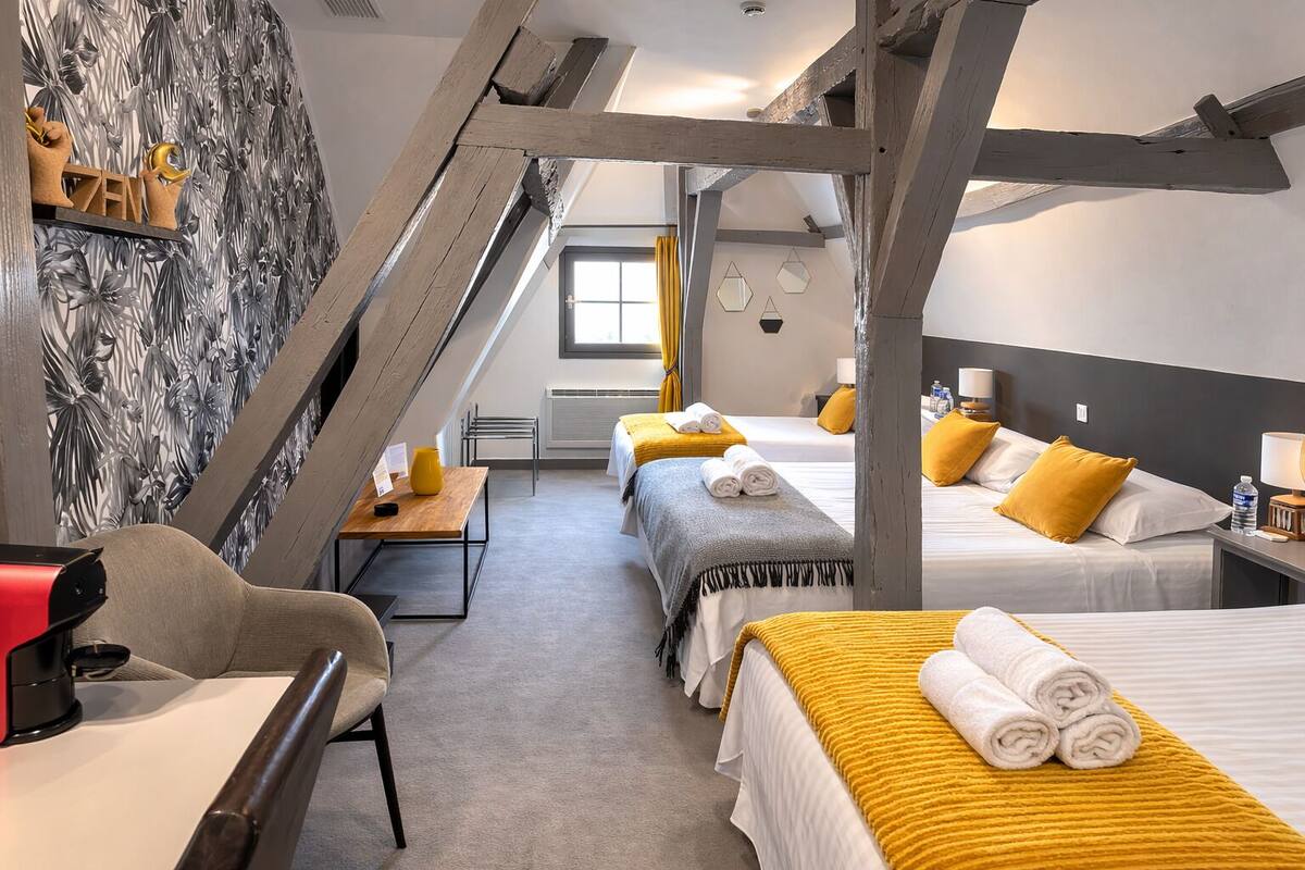 A hotel room with two beds, a desk, a chair, a window, and a decorative wall.
