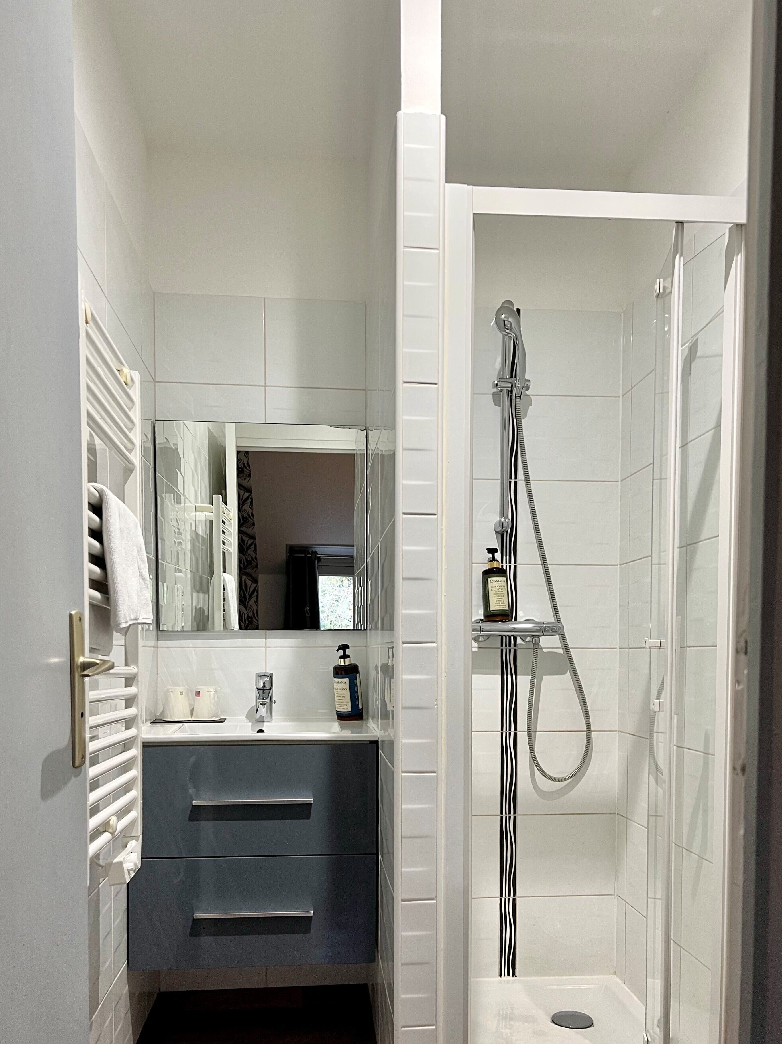 Un baño moderno con ducha, lavamanos y espejo.