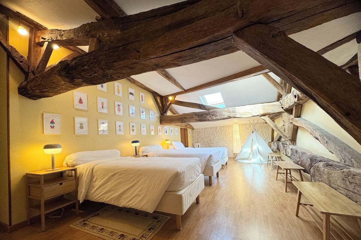 A bedroom with two beds, a wooden bench, a tent, and framed pictures on the wall.