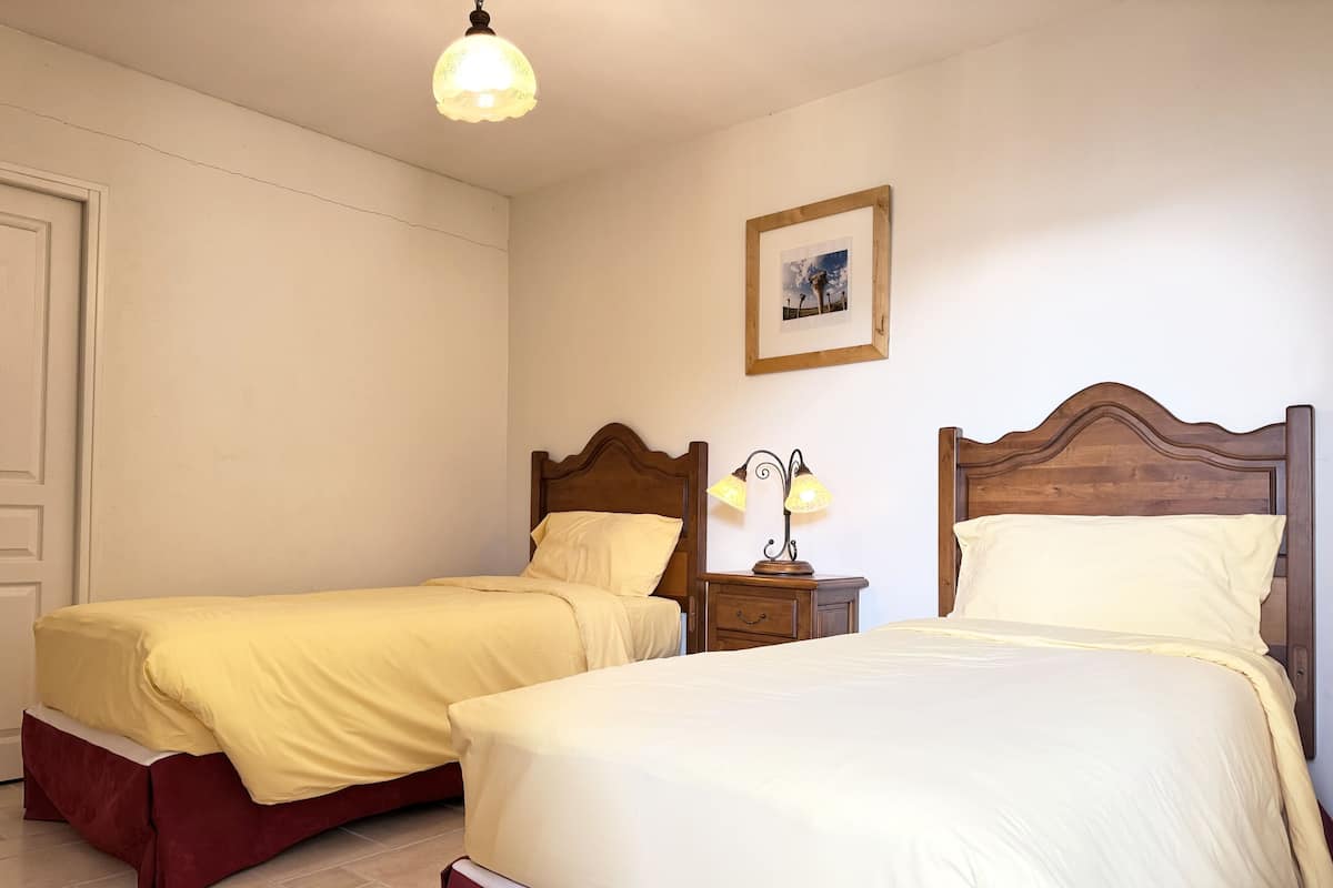 A double bed with a wooden headboard, a bedside table with a lamp, and a framed picture on the wall.