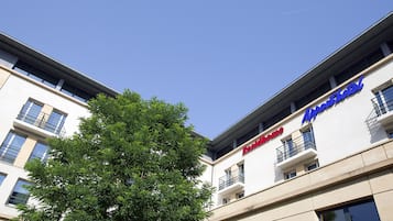 A hotel with a modern facade, balconies, and a clear blue sky.