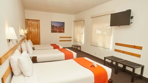 Quarto de hotel com duas camas, uma televisão, um banco de madeira e uma pintura de paisagem urbana.