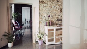 Un pasillo con pared de piedra, un armario blanco con estantes y plantas en macetas.