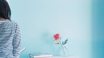 Guests can relax in this serene space, featuring a comfortable bed and a stylish table with a book and a vase.