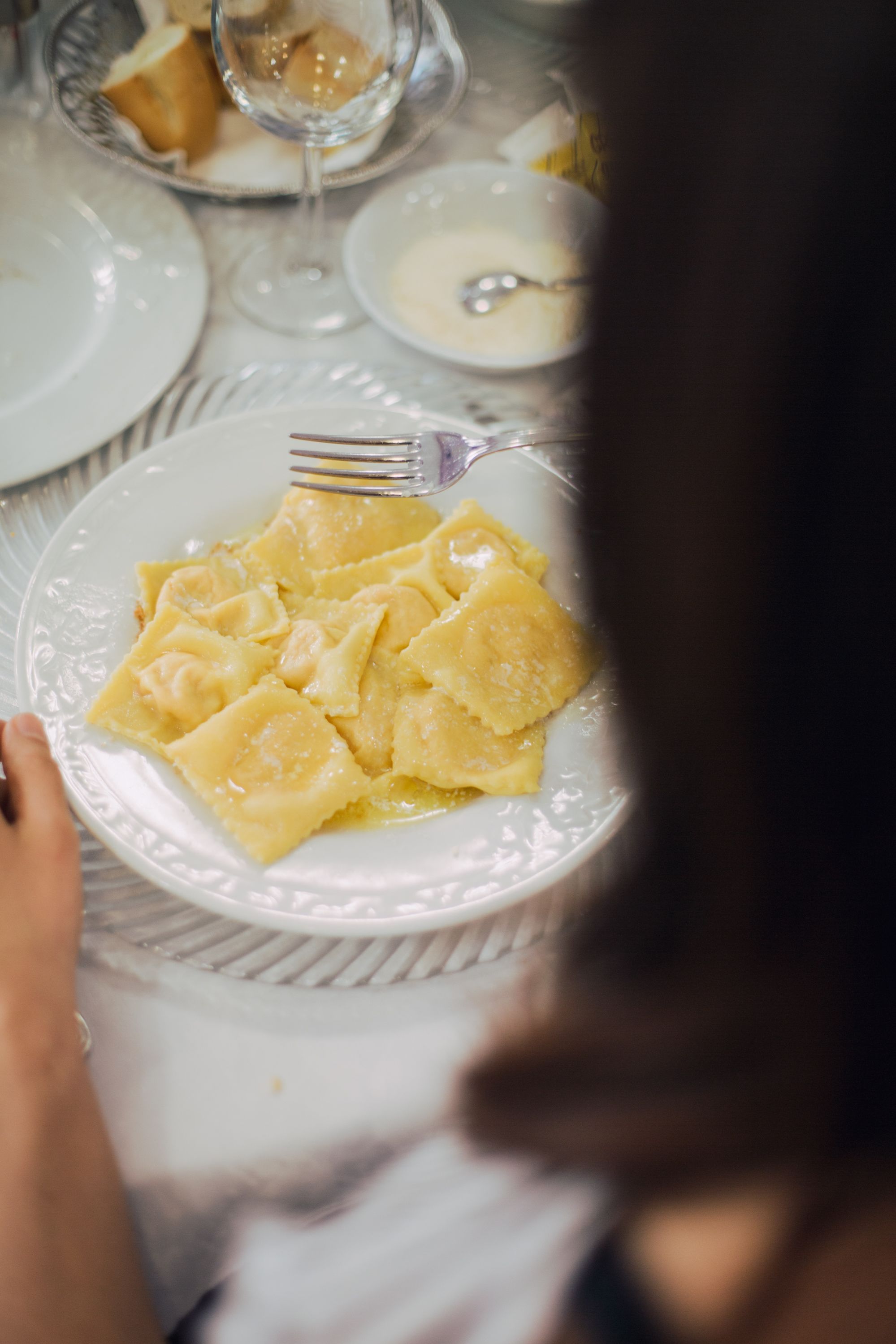 Ein Teller Ravioli mit einer Gabel auf einer weißen Tischdecke.