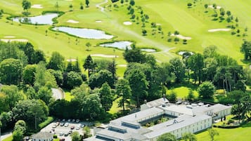 An aerial view of a golf course with a clubhouse and parking area.