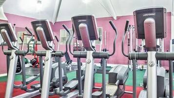 Un gimnasio con máquinas elípticas, suelo verde y paredes rosas.