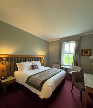 A hotel room with a large bed, bedside tables, a desk, and a chair.