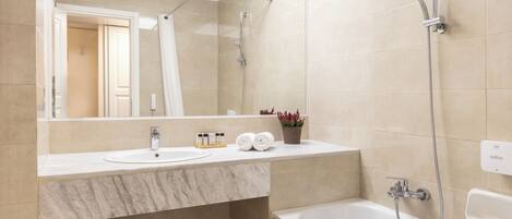 A modern bathroom with a bathtub, a shower, and a sink.