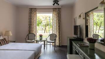 Une chambre d’hôtel avec deux lits, un bureau avec une chaise, une télévision et une vue sur l’extérieur.