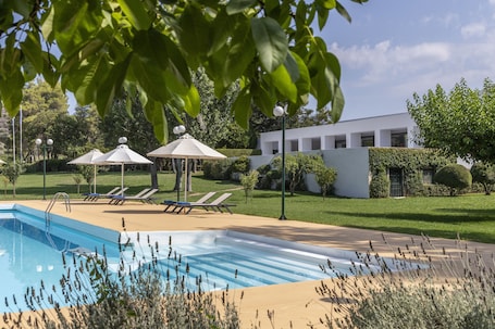 Una piscina al aire libre de temporada, sombrillas