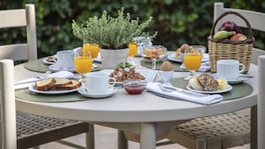 Mesa redonda para refeições com itens de café da manhã, como torradas, ovos e frutas.