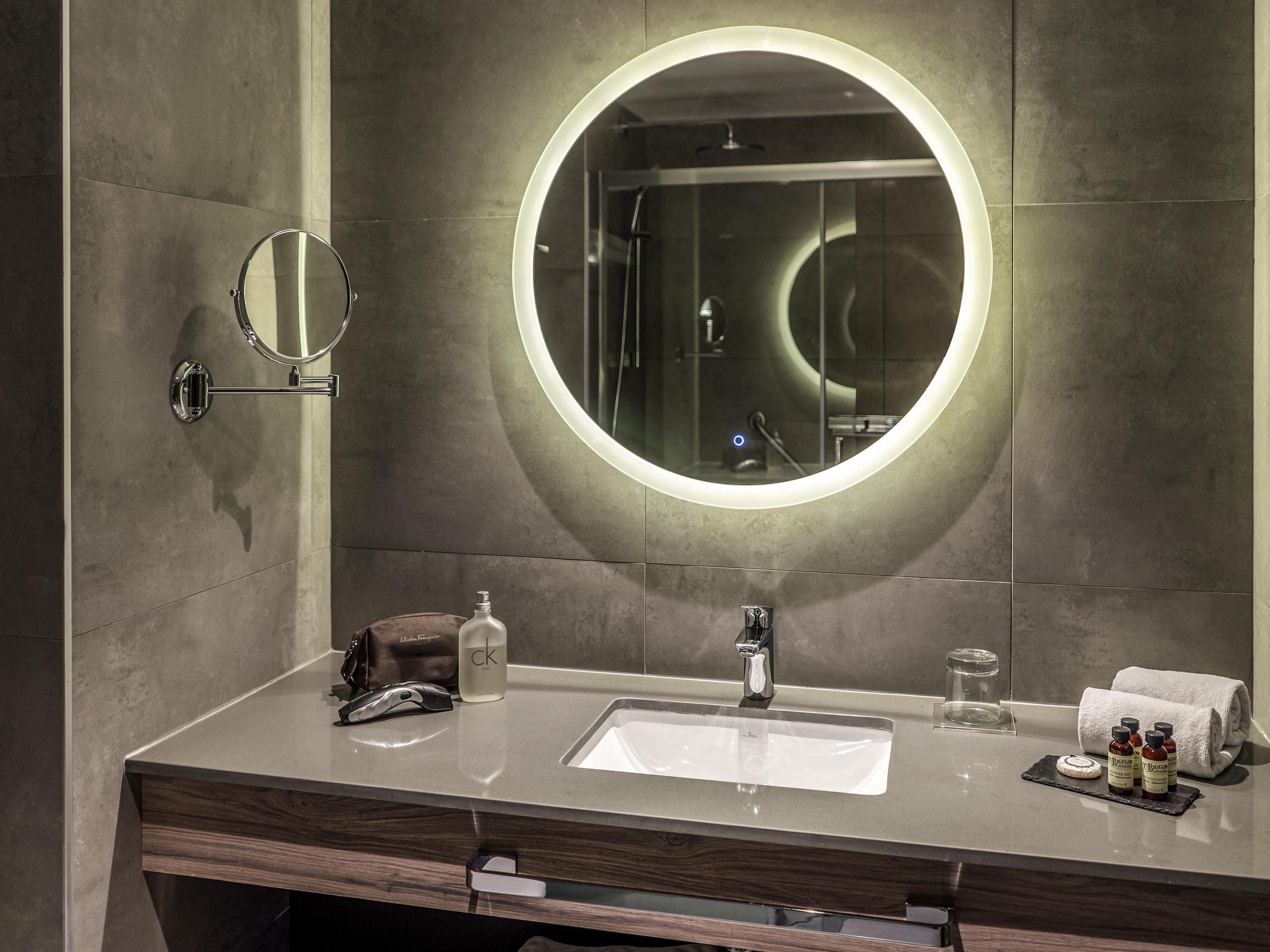 Un baño moderno con un espejo redondo, un lavabo y una zona de ducha.