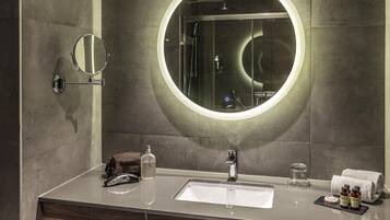 Un baño moderno con un espejo redondo, un lavabo y una zona de ducha.