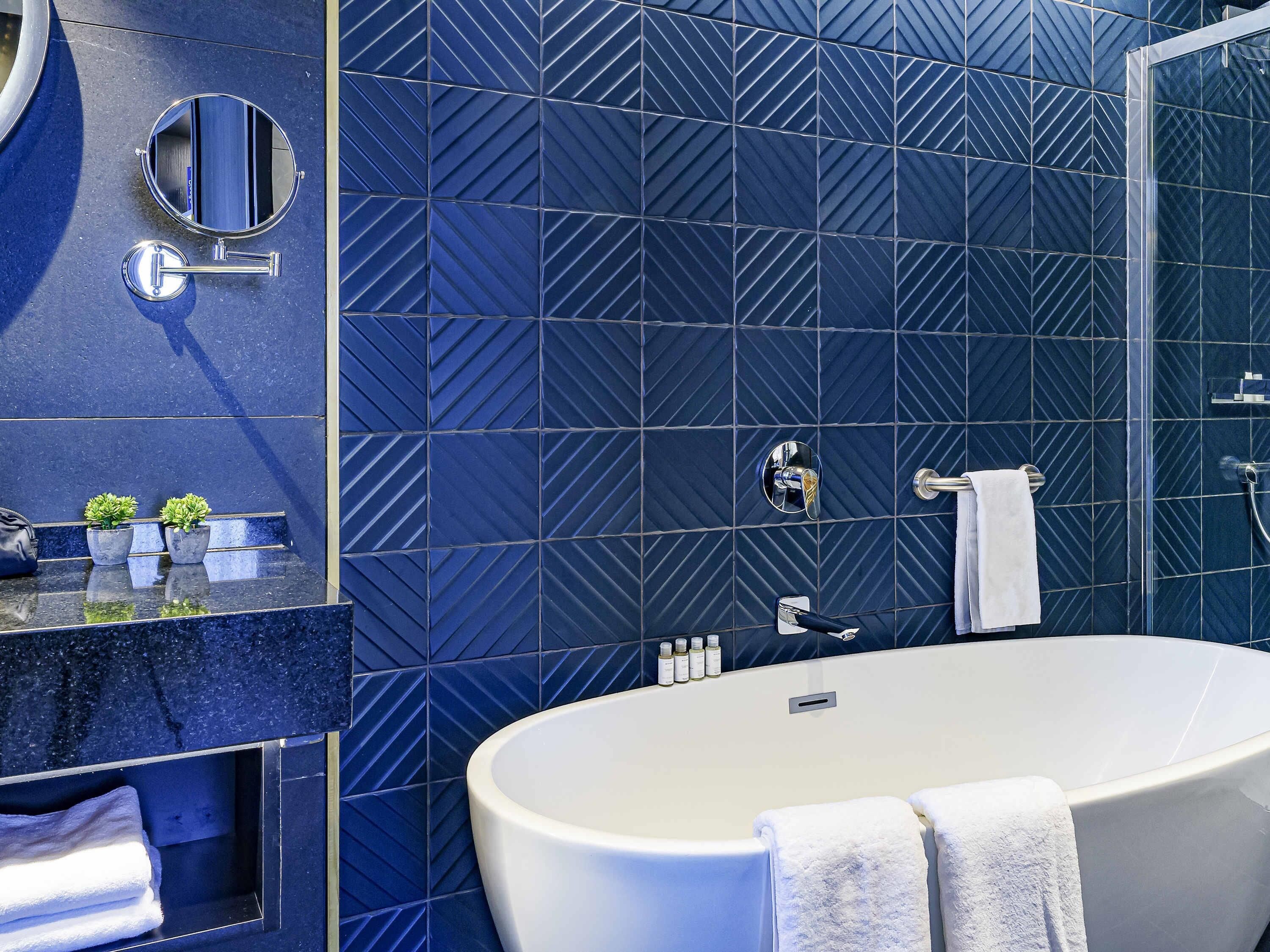 Een moderne badkamer met een vrijstaand bad, een spiegel en een handdoekrek.
