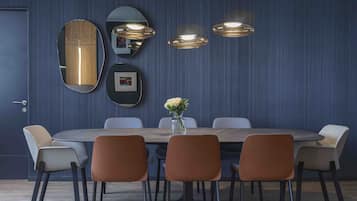 A modern dining area with a round table, six chairs, and a vase with flowers.