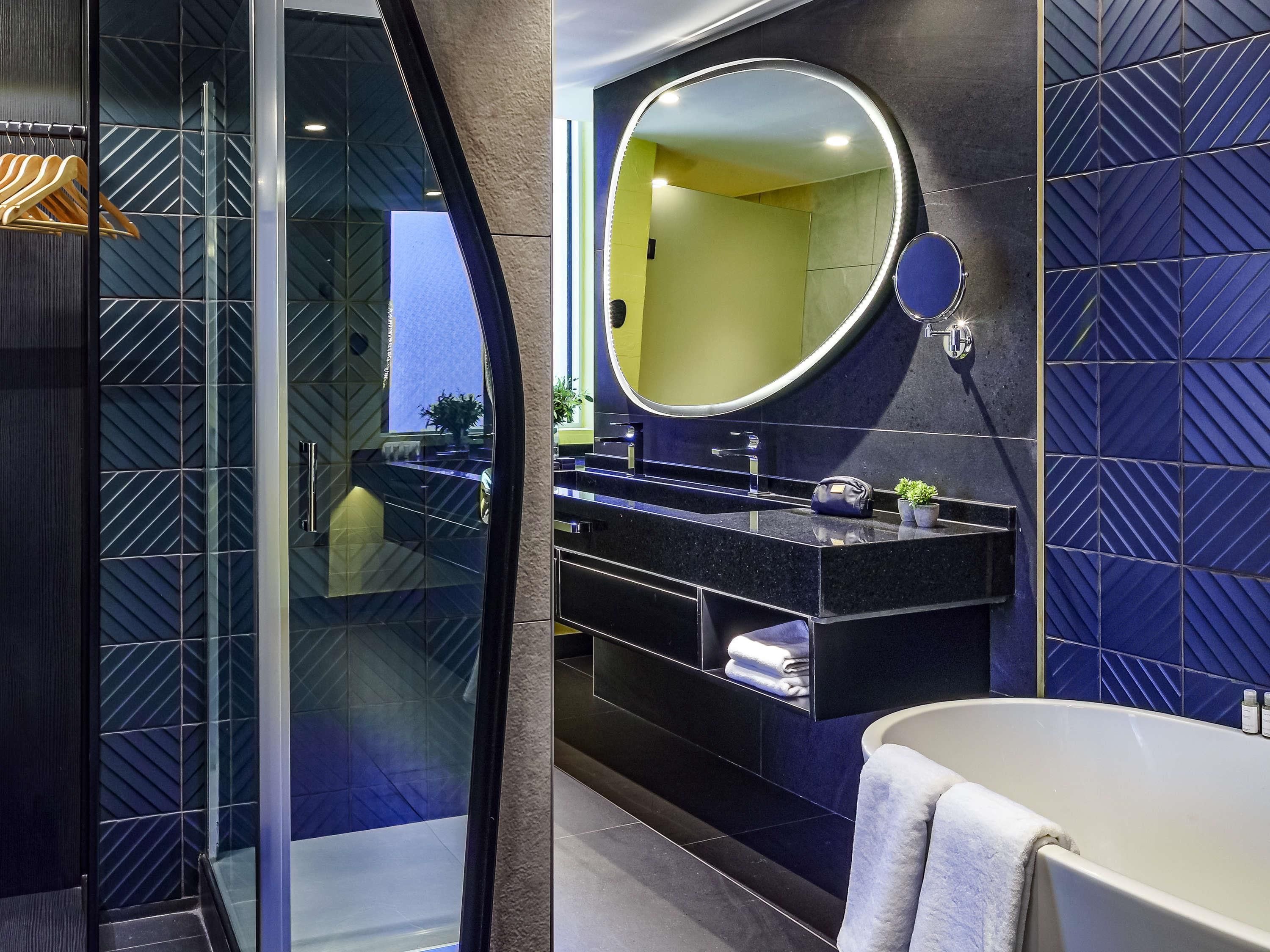 Un baño moderno con cabina de ducha de vidrio, tocador con un espejo grande y bañera.