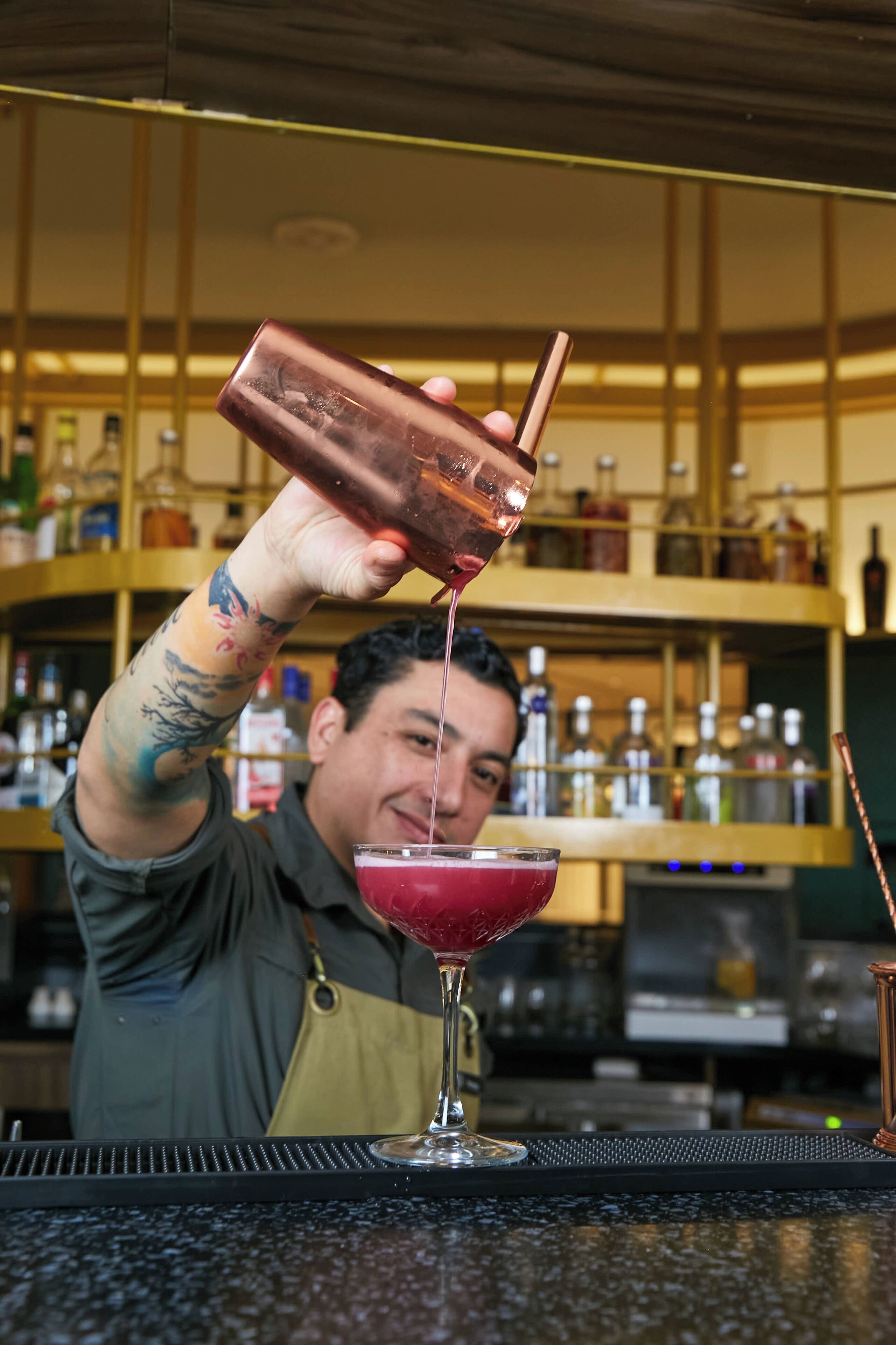 A bartender pouring a drink into a martini glass.