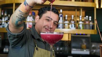 A bartender pouring a drink into a martini glass.